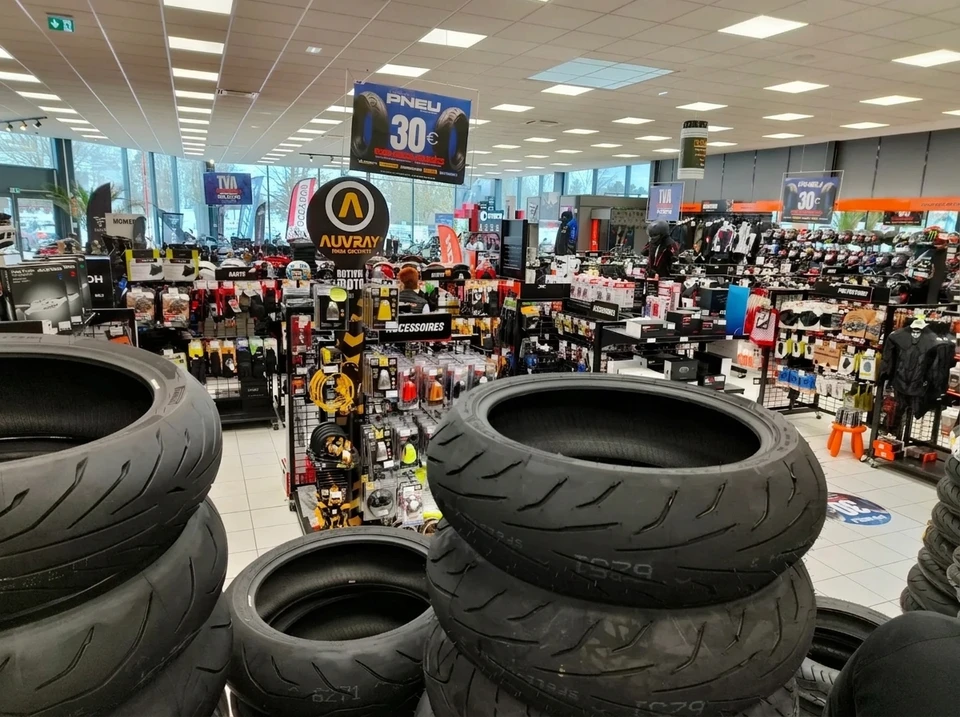 Magasin de moto en intérieur, rayons bien achalandés, présentoirs d'accessoires, casques, équipements et vêtements