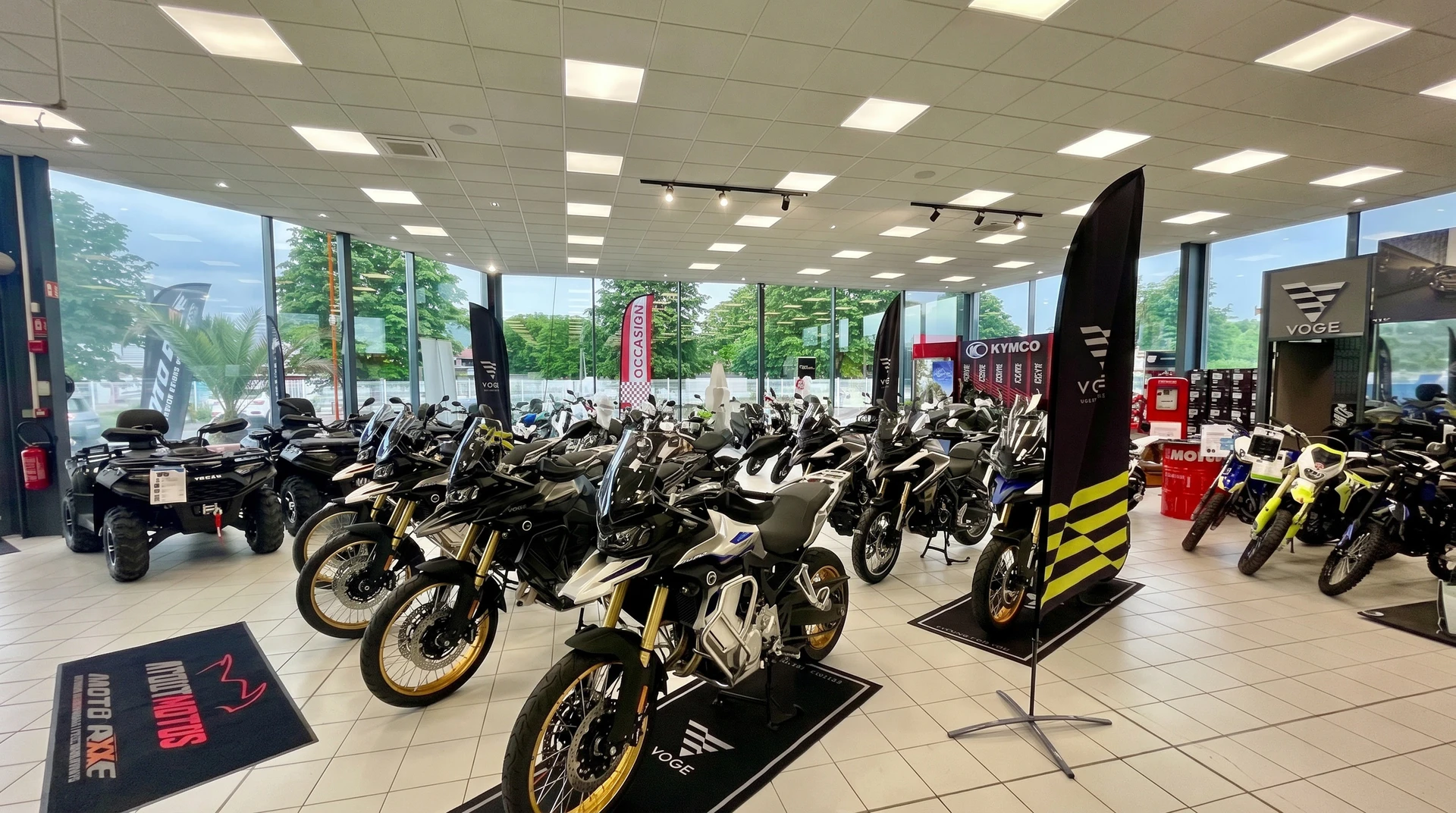 Showroom de motos spacieux et lumineux, vitres panoramiques, sol carrelé beige